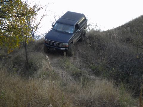 1995 Ford Bronco - Dark blue 1995 Ford Bronco navigates a challenging off-road incline.