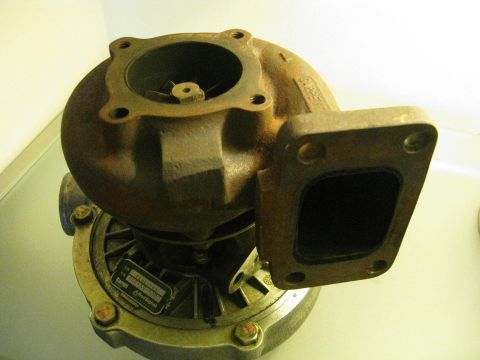 1994 Ford Probe - A close-up view of a rusty turbocharger, identified by a metal tag on its base.