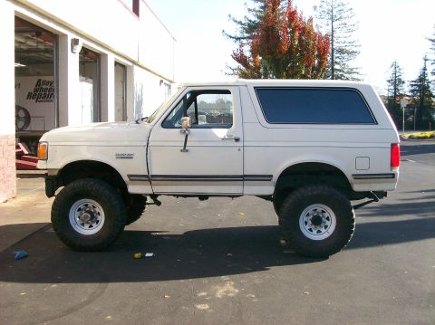 1989 Ford Bronco - This white Ford Bronco, likely from the 1987-1991 model years, is modified with a suspension lift and off-road tires.