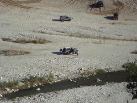 1986 Ford Bronco - Several off-road vehicles navigate a , arid terrain, suggesting an outdoor adventure or trail exploration.