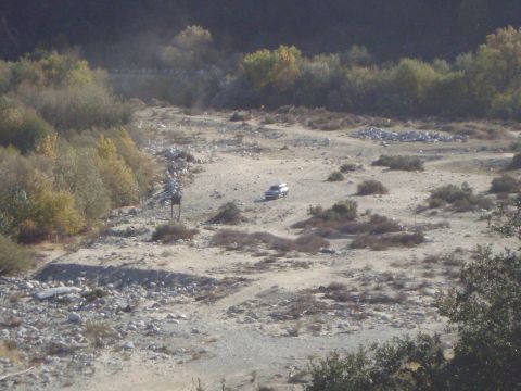 1986 Ford Bronco - SUV driving through a dry riverbed landscape.