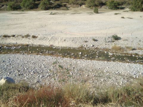 1986 Ford Bronco - A dry riverbed landscape with a dirt road visible on the embankment above.