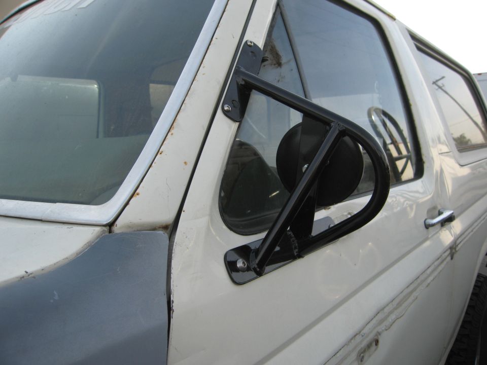 White Ford Bronco with aftermarket side mirror and dark fender