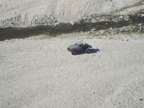 1986 Ford Bronco - A remote control truck is parked on a gravelly surface near a small stream bed.