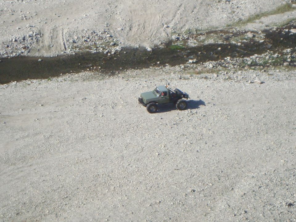 small remote control truck on a dirt road next to a dry creek bed