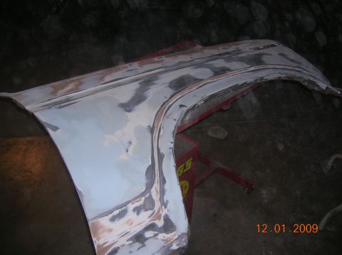 1985 Ford Bronco - A vehicle fender is being prepped for paint with body filler and sanding marks visible.