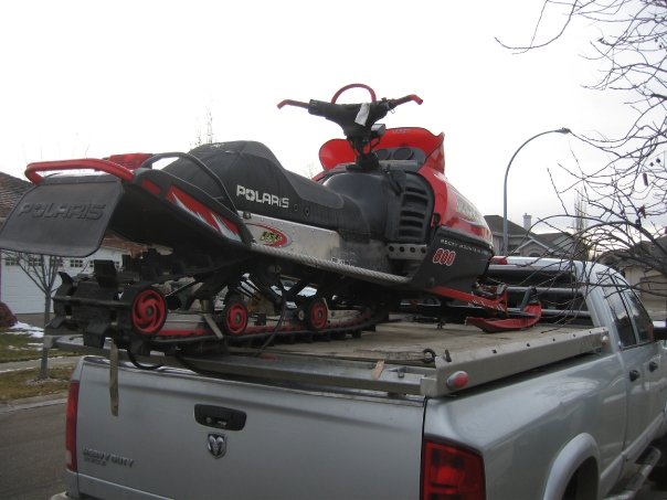Red and black Polaris snowmobile loaded on a silver Dodge pickup truck