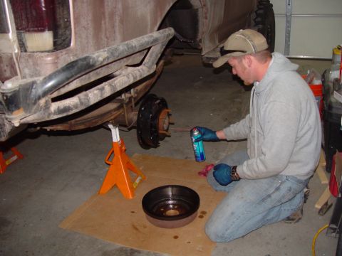 1993 Ford Bronco - A person is performing maintenance on the rear brake assembly of a vehicle.