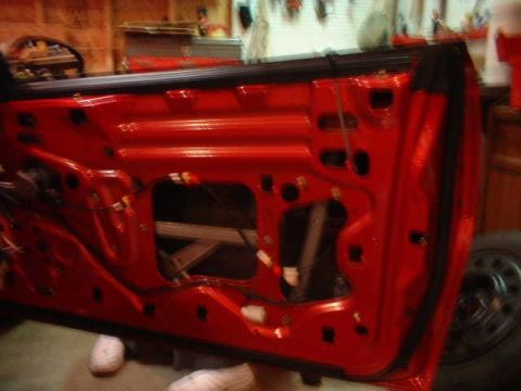 1994 Ford Mustang - Interior view of a red car door panel, showing internal mechanisms and wiring.