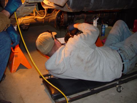 1993 Ford Bronco - Mechanic performs rear axle service on a vehicle supported by jack stands.