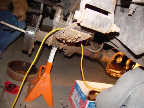 1993 Ford Bronco - Working on the rear axle assembly of a vehicle, with brake components and wiring in view.