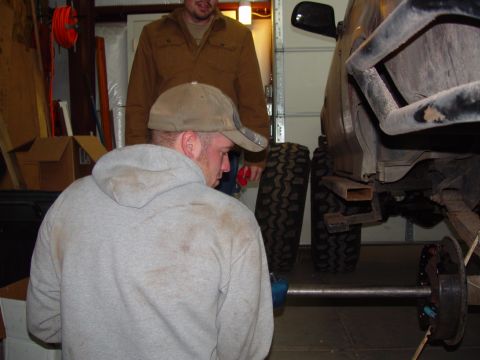 1993 Ford Bronco - Mechanics work on the rear axle assembly of a 1993 Ford Bronco in a garage.