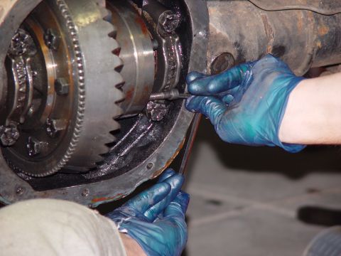 1993 Ford Bronco - Mechanic's hands in gloves carefully adjust components within a vehicle's differential.