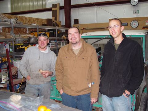1993 Ford Bronco - Three men stand in a garage, with a teal 1978 Ford Bronco partially visible behind them.