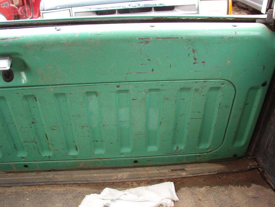 Green tailgate panel of a pickup truck viewed from inside a garage