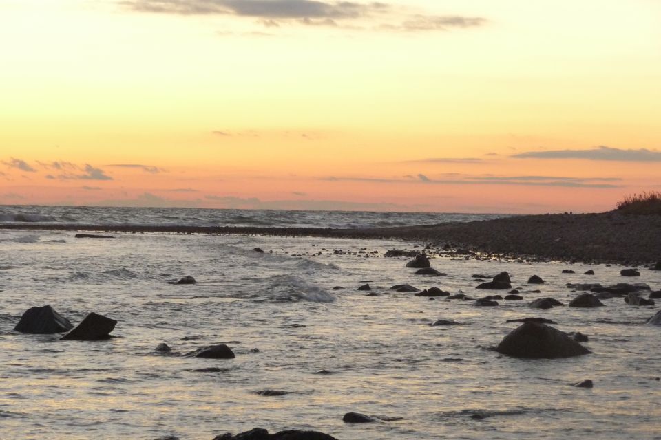 Rocky shoreline with waves under a colorful sunset sky