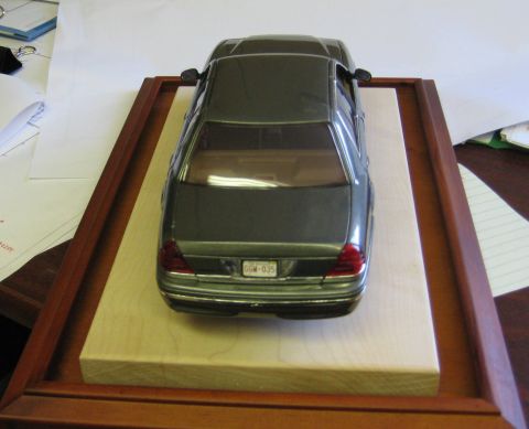1999 Ford Crown Victoria - A detailed model of a 1999 Ford Crown Victoria is displayed on a wooden base.