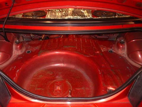1994 Ford Mustang - The interior of a car's trunk is shown, with red paint and some soundproofing material visible.