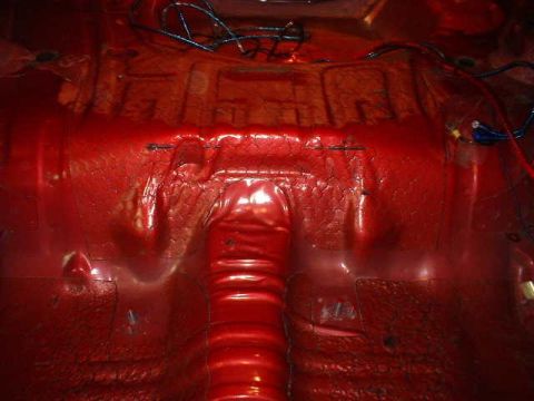 1994 Ford Mustang - The red-painted interior of a 1994 Ford Mustang's rear floor pan shows sound deadening material and wiring.