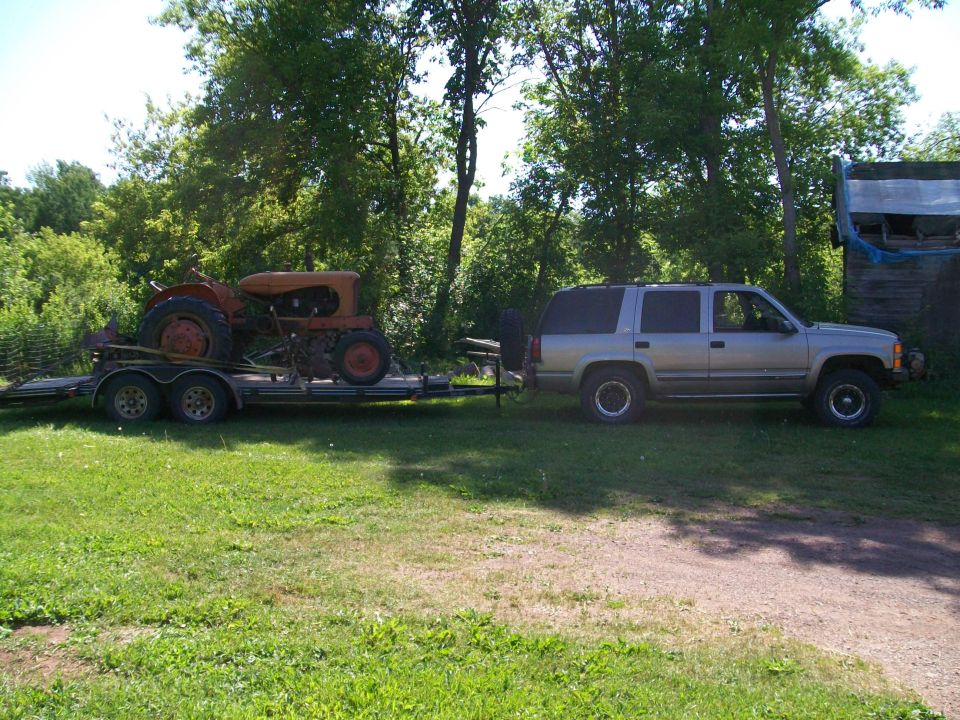 Silver SUV towing a trailer with an orange tractor