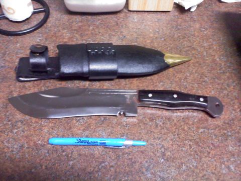 1977 Ford F-100 - A large knife and its sheath are displayed on a speckled countertop next to a blue pen.