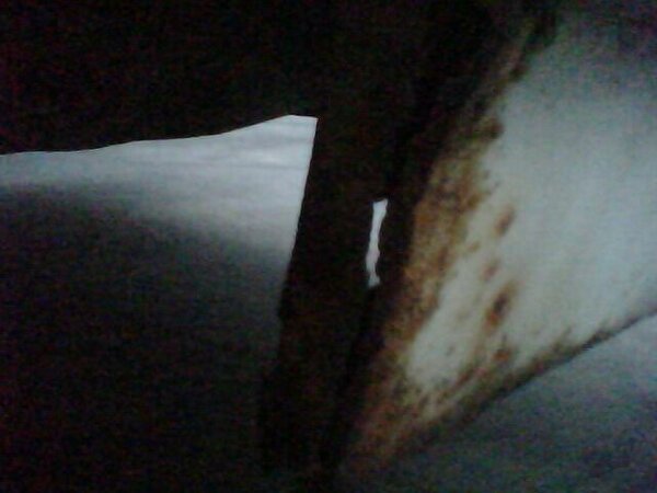 Rusted metal panel with white paint and dark background
