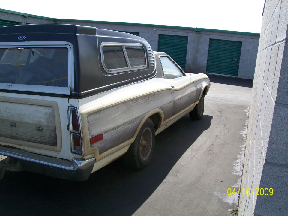 1972 Ford Ranchero with wood paneling and a black camper shell, viewed from the rear-left