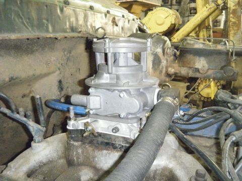 1978 Ford Bronco - Close-up view of engine components, including a carburetor and brake master cylinder, in a garage setting.