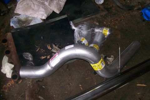 1992 Ford C-350 (Centurion Conversions) - A new exhaust pipe system is laid out on a cluttered garage floor, ready for installation.