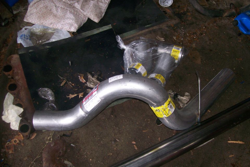 New exhaust pipe system with yellow labels on a garage floor