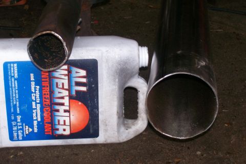 1992 Ford C-350 (Centurion Conversions) - Two metal pipes and a jug of antifreeze are shown in this close-up view.