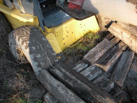 1996 Ford Bronco - A yellow tractor is stuck in the mud, with wooden planks scattered around it.