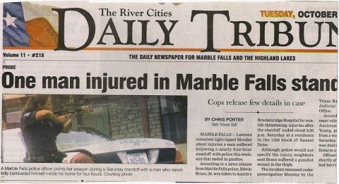 2001 Ford Crown Victoria - A newspaper article details a police standoff, a photo of a police car and an officer.