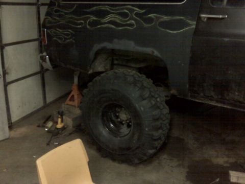 1992 Ford F-350 - This modified truck is being worked on in a garage, custom flame graphics and oversized tires.