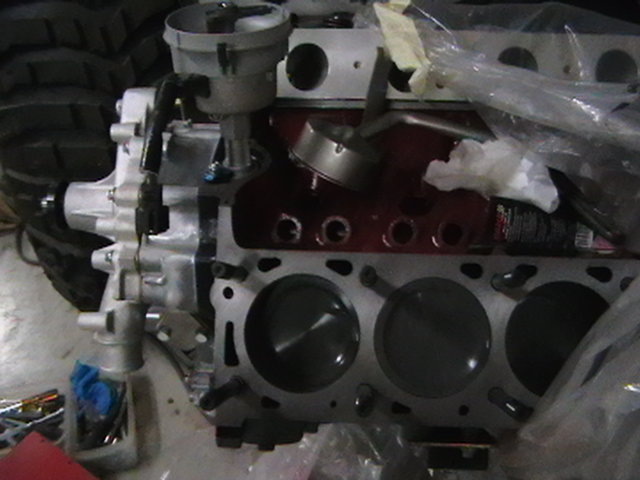 Disassembled V6 engine block showing cylinder bores and pistons on a workbench