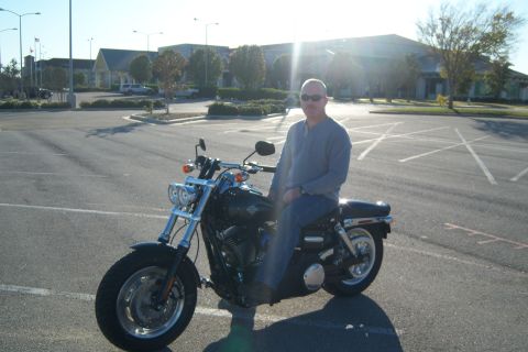1996 Ford Bronco - A man poses on his motorcycle in an empty parking lot on a sunny day.