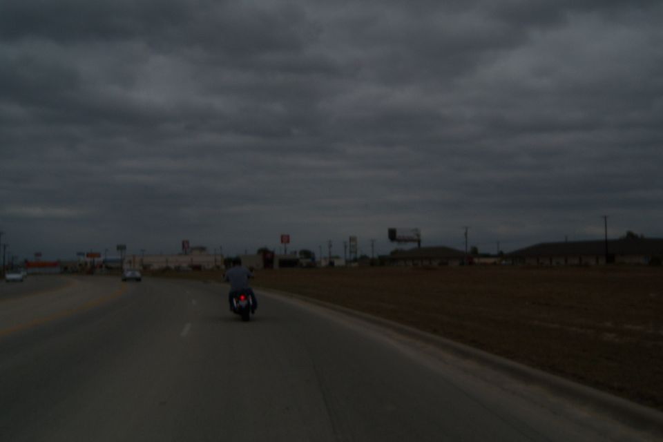 Motorcycle on highway under cloudy sky, other cars visible in distance