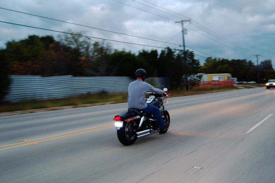 Guy on a motorcycle riding down a road. Cloudy sky
