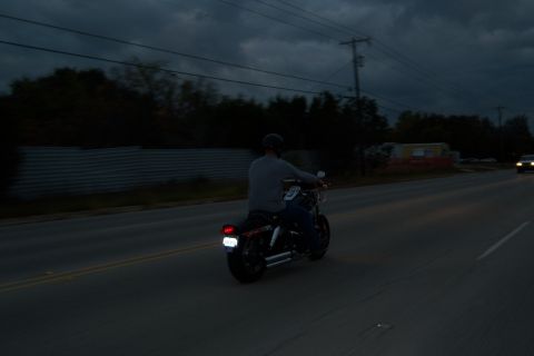 1996 Ford Bronco - A motorcycle rider travels down a road as dusk settles, with another vehicle visible ahead.