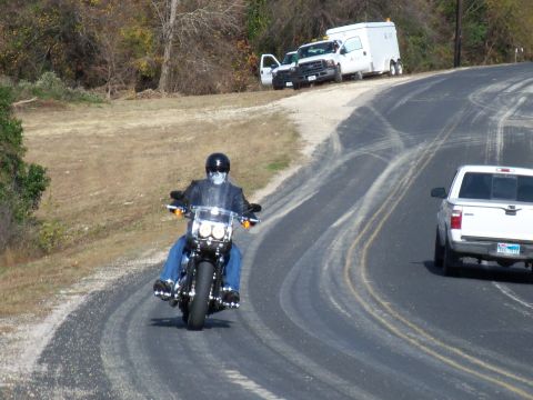 1996 Ford Bronco - A motorcyclist wearing a skull mask navigates a curved road, with two trucks visible in the distance.
