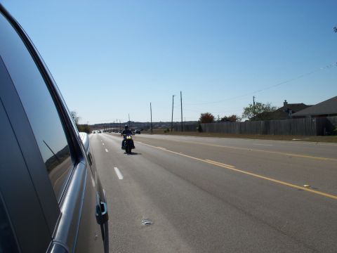 1996 Ford Bronco - A motorcycle rides down a highway on a clear day, seen from the perspective of a passing car.