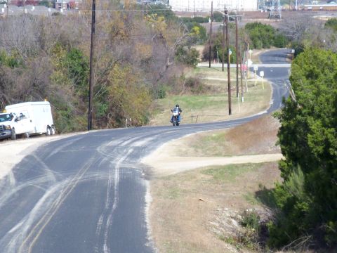 1996 Ford Bronco - A motorcycle cruises down a rural road, with a utility truck parked nearby.