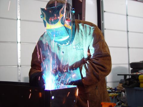 1993 Ford Bronco - A welder works on a metal project, sparks flying, in a workshop setting.
