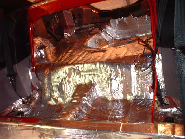 Car floor pan and tunnel covered in foil sound deadening mat, seats and carpet removed