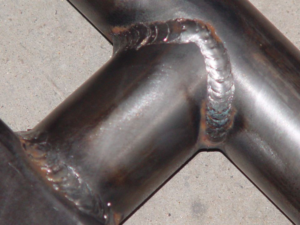 Close-up of welded metal tubing joints on a gray concrete surface