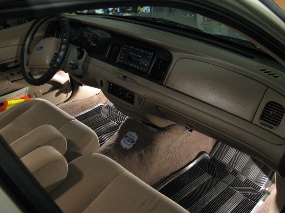 Tan Ford Crown Victoria interior with bench seat, dash and Police Interceptor badge on the floor hump