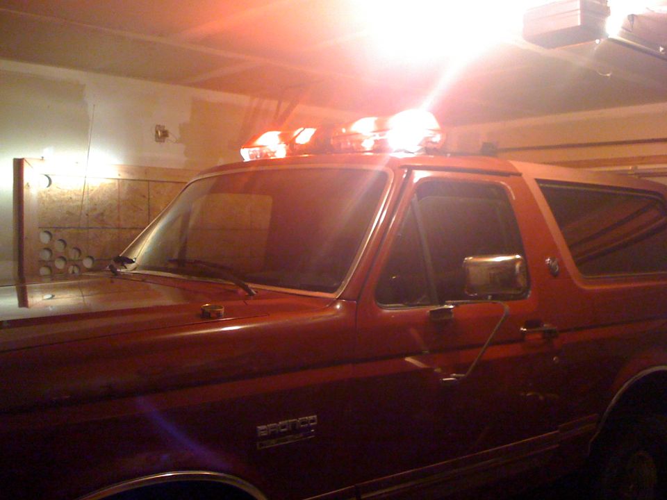 Red Ford Bronco with roof light bar parked inside a garage