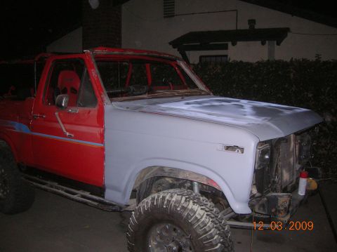 1985 Ford Bronco - This SUV, likely from the early 1980s, is in the process of body repair, with one fender primed and the rest of the body red. A date stamp…