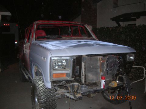 1985 Ford Bronco - Ford Bronco undergoing restoration, front end disassembled, showing primer and exposed engine components.