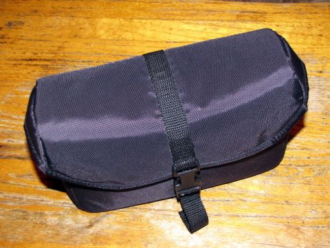 1984 Ford Bronco - A black canvas bag with a strap is shown on a wooden surface.